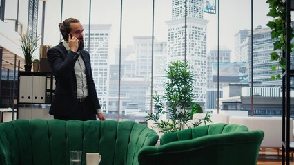 CEO multitasking and managing an important phone call with investors while he reviews financial...