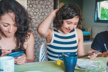 Happy young Latin women enjoying a healthy breakfast while seated in the dining room of their modern apartment. Healthy lifestyle and nutrition concept.