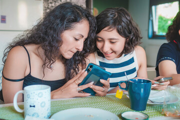 Happy young Latin women enjoying a healthy breakfast while seated in the dining room of their modern apartment. Healthy lifestyle and nutrition concept.