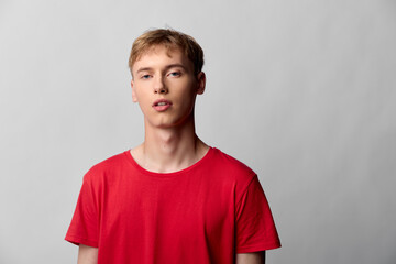 Fototapeta premium Youth, man, red shirt, casual studio expression with minimal neutral background and clean lighting for fashion oriented stock image highlighting confidence and modern style in a simple indoor setting