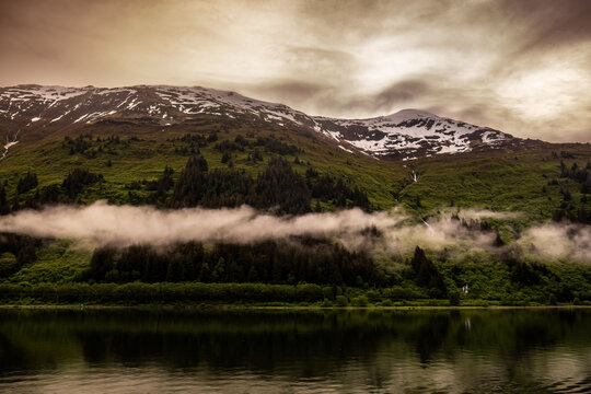 A dramatic view of both snow and lush greenery on a mountainside near Juneau, Alaska.