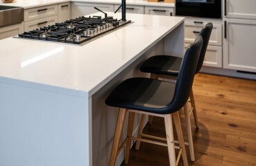 Kitchen island with built-in gas cooktop and two modern bar stools on wood flooring