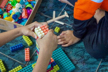 Fototapeta premium Children are playing with colorful plastic building blocks on the tiled floor, creativity and interaction as they play with these educational toys 