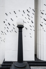 Scary and creepy Halloween background, exterior of white building decorated with a cauldron of plastic bats flying across the scene
