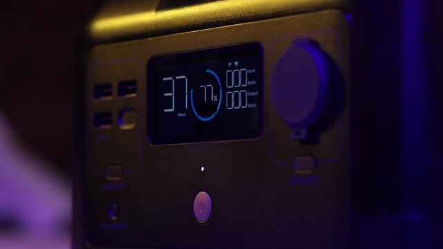 Close-up of a portable power station's digital screen displaying remaining hours, battery percentage, and input/output wattage information