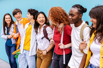 Happy diverse teen students hanging out , leaning on campus building college wall. Youth and education concept