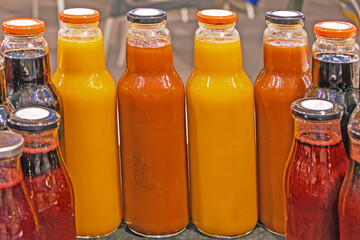 Freshly squeezed colorful fruit juices in glass bottles on market 