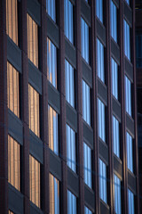 Modern high-rise facade with reflective glass and geometric grid in urban environment
