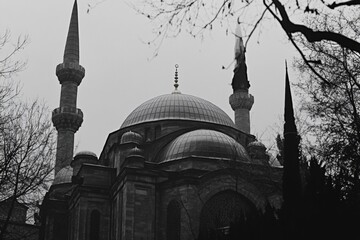 Majestic dome and minaret silhouettes against cloudy sky.