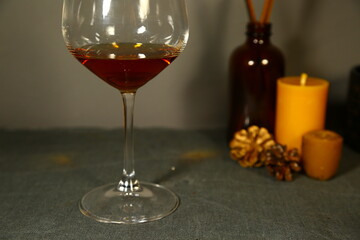 Glass of gold brandy and candle on grey background with empty copy space. Closeup decor celebration portrait