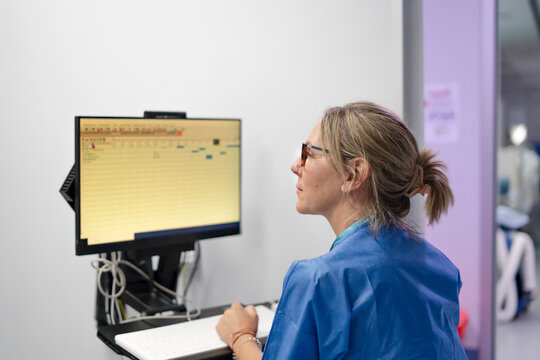 Nurse entering medical data on computer in clinic