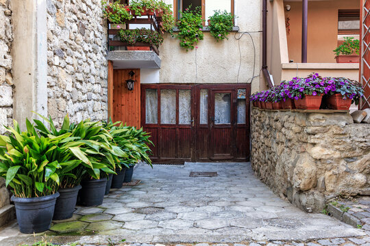 Quaint stone courtyard with wooden doors and lush potted plants