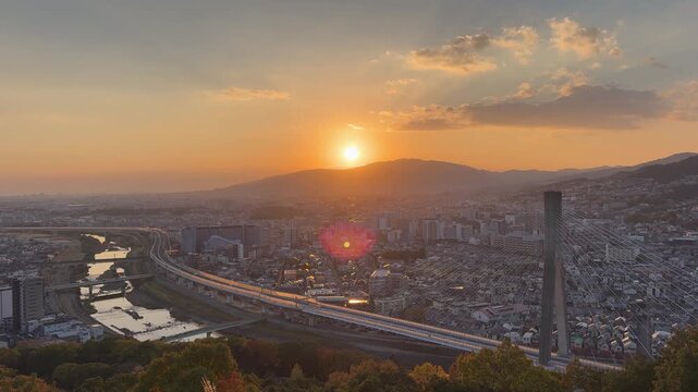 Cinematic Wide Shot of the Sun Setting Behind Mountains Overlooking the Dense Metropolitan Landscape of Ikeda Osaka
