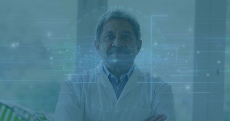 Standing senior doctor wearing white lab coat in clinic, crossing arms and showing blue HUD overlay