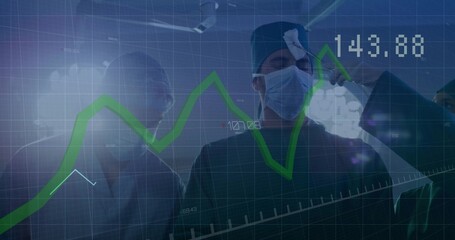 Operating surgeon guiding team in OR under lights, wearing scrubs and masks with green chart 143