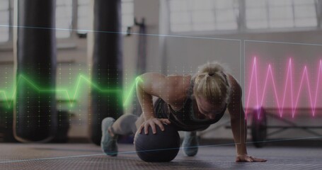 Holding med ball, woman in leggings performing pushup on rubber floor at gym with waveform graphics