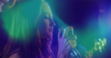 Singing female vocalist holding vintage microphone near mouth in haze, wearing dark clothing