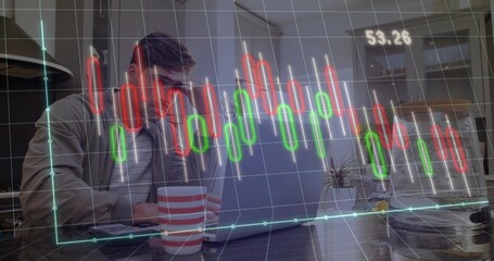 Typing man in jacket in kitchen holding red-and-white mug using laptop, chart, copy space