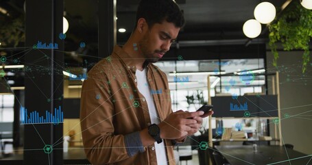 Standing man in brown overshirt checking phone with wristwatch in open-plan office, data overlay