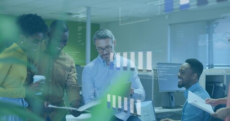 Discussing five coworkers reviewing data on monitors in open office wearing hoodie and holding cup