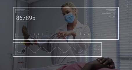 Examining clinician wearing white lab coat and surgical mask lifting patient leg on exam table, HUD