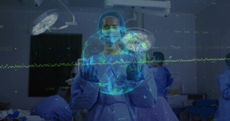 Gesturing masked gloved surgeon in gown cap interacting with holographic globe and ECG trace in OR