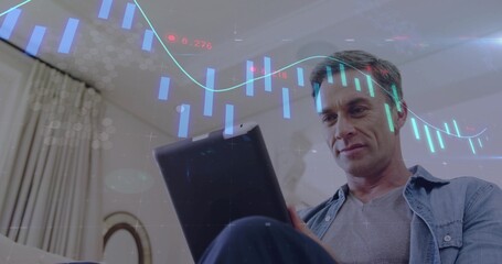 Holding tablet, mature man studying finance overlays in living room on sofa, denim shirt grey-tee