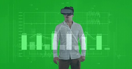 Experiencing man in white shirt dark pants viewing data charts at green backdrop, with VR headset