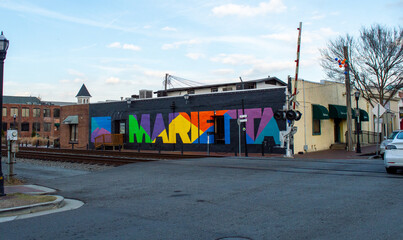 Colorful Large Marietta Town Mural Painted on a Dark Brick Wall Located Near Railroad Tracks in a Historic Downtown Area Under a Clear Blue Sky, Perfect for Travel and Local Tourism Promotion. © Michael