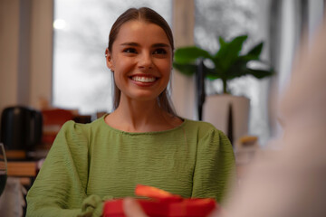 Happy woman smiling widely receiving a red gift box on a date