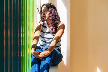 A woman sits on a ledge with her hands on her knees