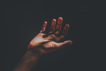 Close up of an open palm under light in the dark. Dramatic light illuminates the center of the palm.