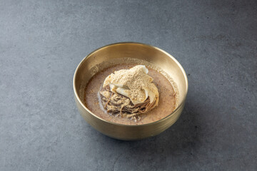 Korean Cold Soy Milk Noodles in Brass Bowl on Stone Background 놋그릇에 담긴 한국식 콩국수