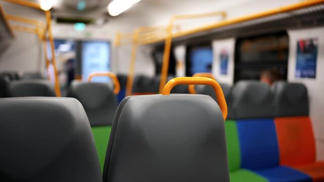 Empty public transport train car interior showcasing colorful seats and yellow handles