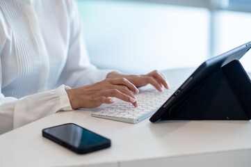 Hands of business woman typing on keyboard use tablet and smartphone