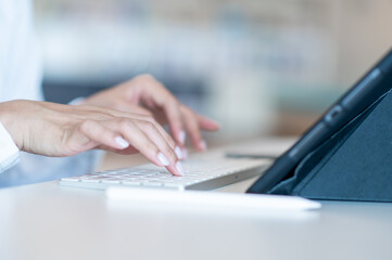 Close up shot of woman's hands typing on keyboard using tablet