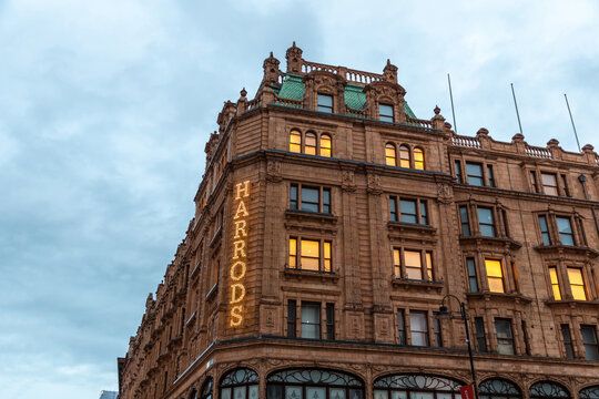 Illuminated Harrods department store facade at night in London, England, UK