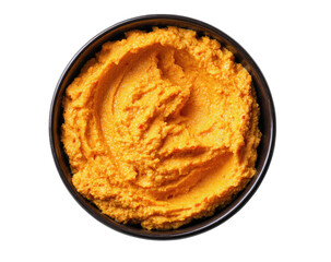 Close-up of a vibrant orange dip in a dark bowl, isolated on black