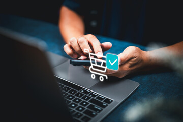 Person using smartphone for online shopping with laptop on table