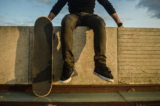 piernas de un hombre joven junto a una patineta