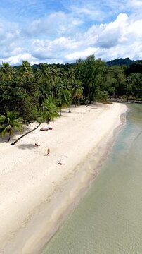 Aerial views reveal the untouched beauty of Koh Kood Island with soft white sands and crystal-clear waters. Lush green palms frame the serene beach, creating a tropical escape in Thailand