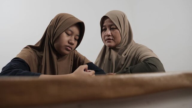 Muslim mother providing emotional support to her upset teenage daughter