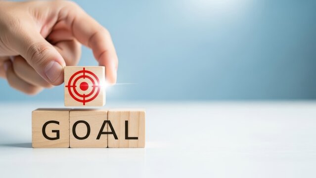 Hand placing wooden block with target symbol on blocks spelling goal