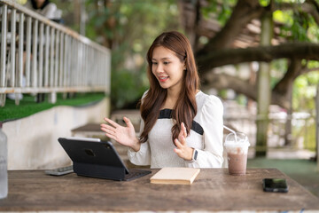 Asian woman having video call on tablet in cafe