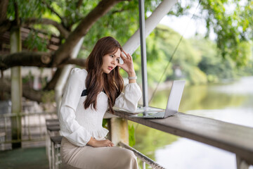 Stressed woman experiencing headache while remote working at outdoor cafe