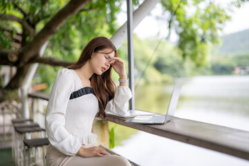 Asian woman experiencing headache from remote work burnout outdoors