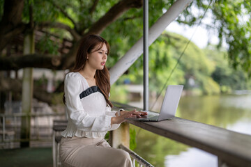 Woman working on laptop outdoors by lake