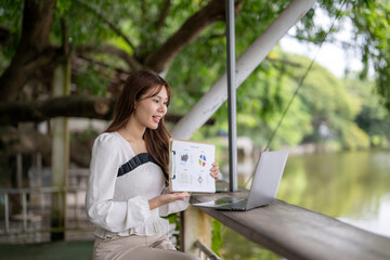 Young woman presenting charts during video call outdoors
