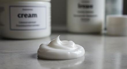 White cream on a gray surface with cream containers in the background