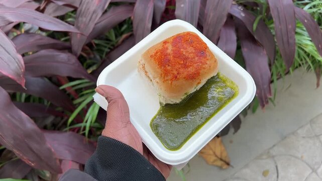 Spicy Indian Vada pav sold in roadside stall with green Chutney